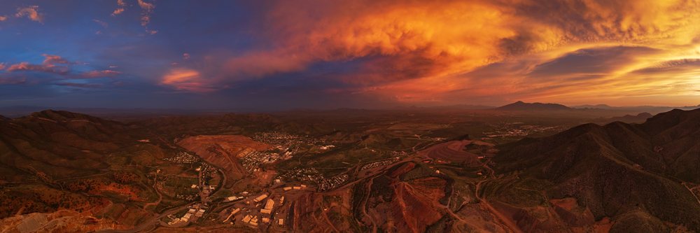 Open pit copper mine at Dusk with orange sunset clouds over mountains and the mining town of, Storm Chasing, Weather, Environmental Issues, Bisbee, Arizona, USA.