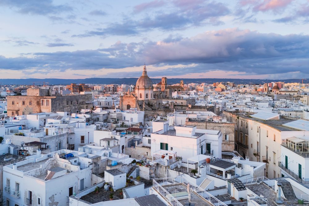 City rooftops with church dome under a blue sky at sunrise, Monopoli, Puglia, Italy.