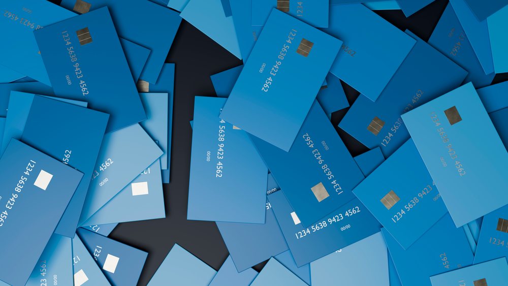 Multiple blue credit cards with visible chips and numbers scattered on a black surface.