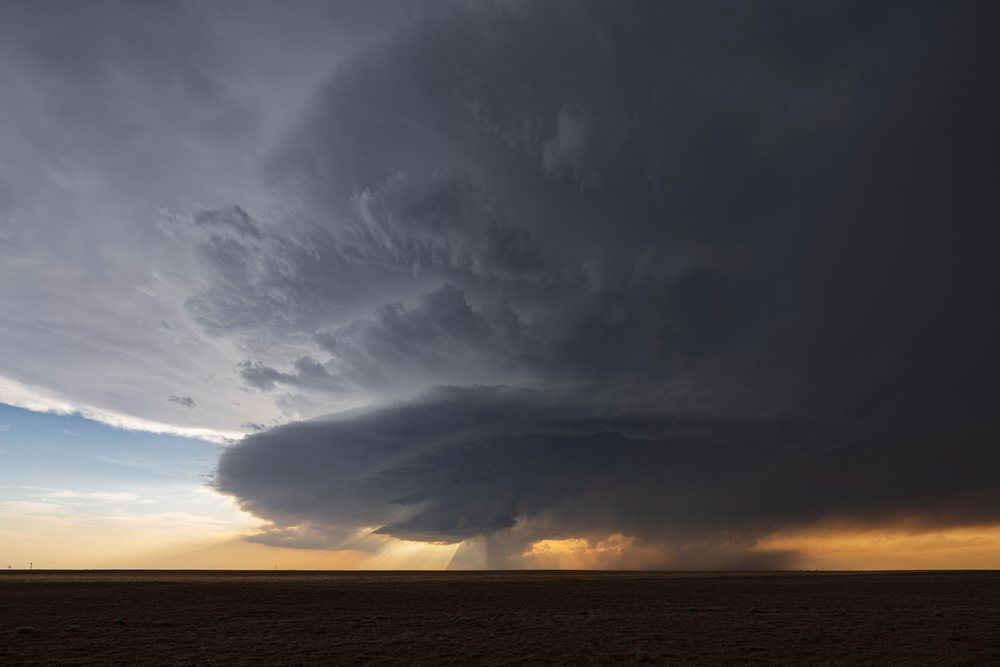 Supercell storm cloud forming over a flat landscape at sunset with sunlight filtering through clouds, Storm Chasing, Weather, Environment, Olney Springs, Colorado, USA.