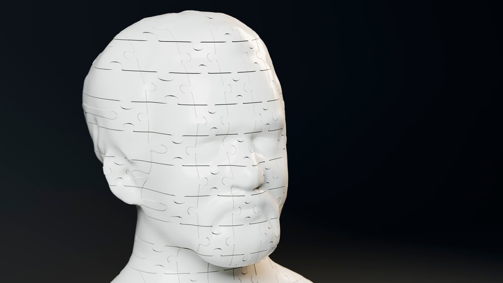 White puzzle pieces assembled to form a human head sculpture on a black background.