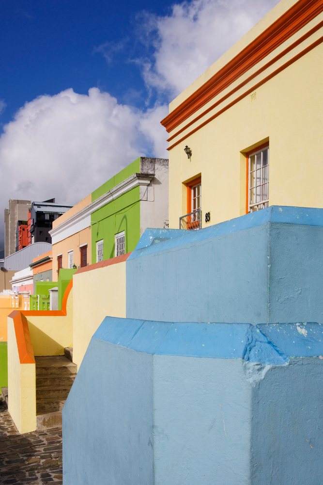 Colorful painted buildings in the Bo Kaap Cape Malay District of Cape Town under a blue sky with clouds and sunlight, Western Cape, South Africa.