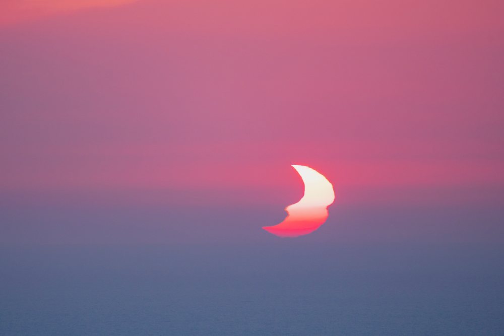 Partially Eclipsed Sun at sunset over the sea with red sky, Landscape, Lifestyle, Valldemossa, Mallorca, Spain.