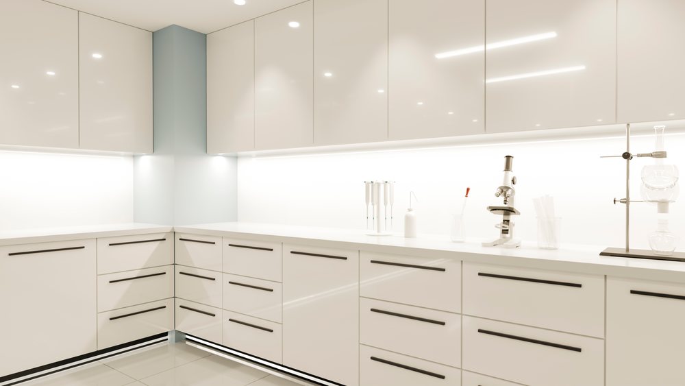 Microscope, pipettes, and glassware arranged on a clean white laboratory countertop in a modern science lab setting.