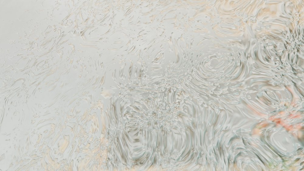 Water droplets creating ripples and patterns on a wet surface with rainwater, showcasing fluid motion and texture.