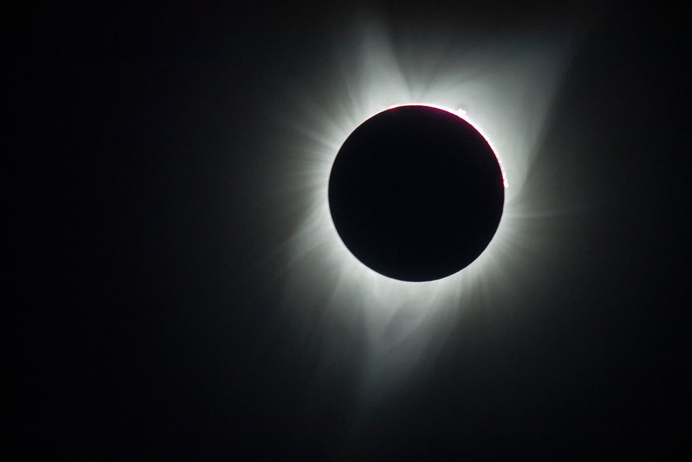 Solar eclipse with visible sun corona and prominences over the dark sky, Los Angeles, USA.