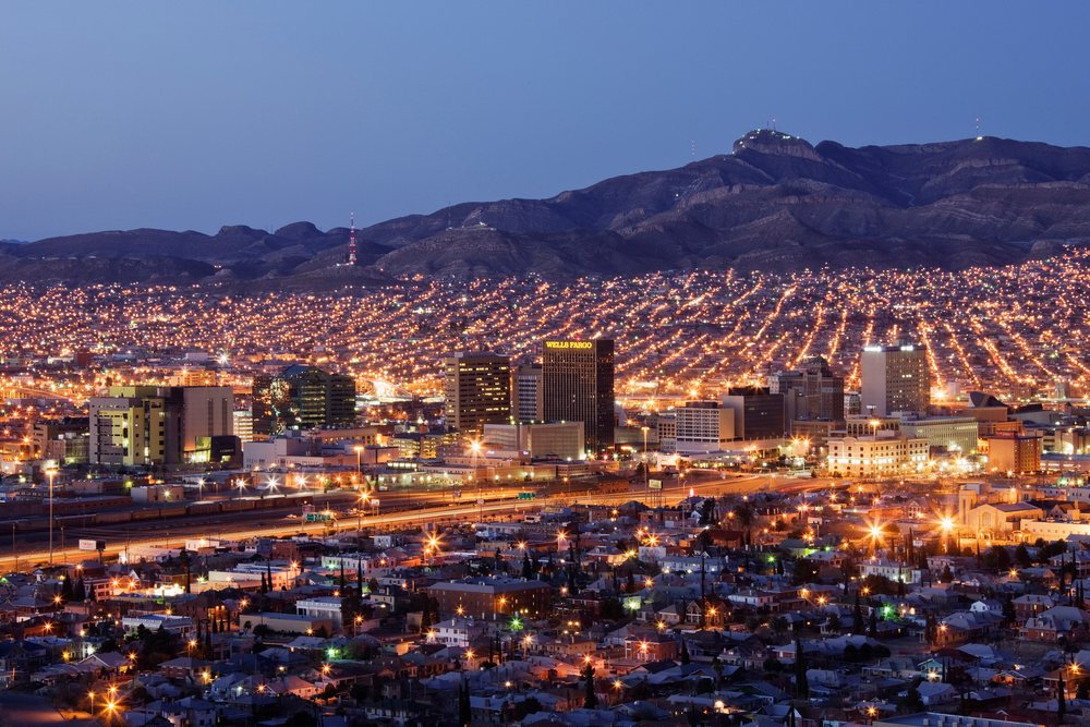 El Paso cityscape illuminated at dusk with mountains in the background under a clear sky.