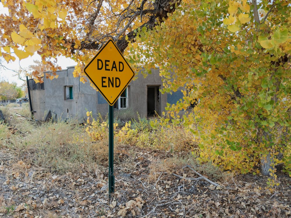 Dead end traffic sign stands before an old abandoned building, Americana, Historic, San Fidel, New Mexico, USA.