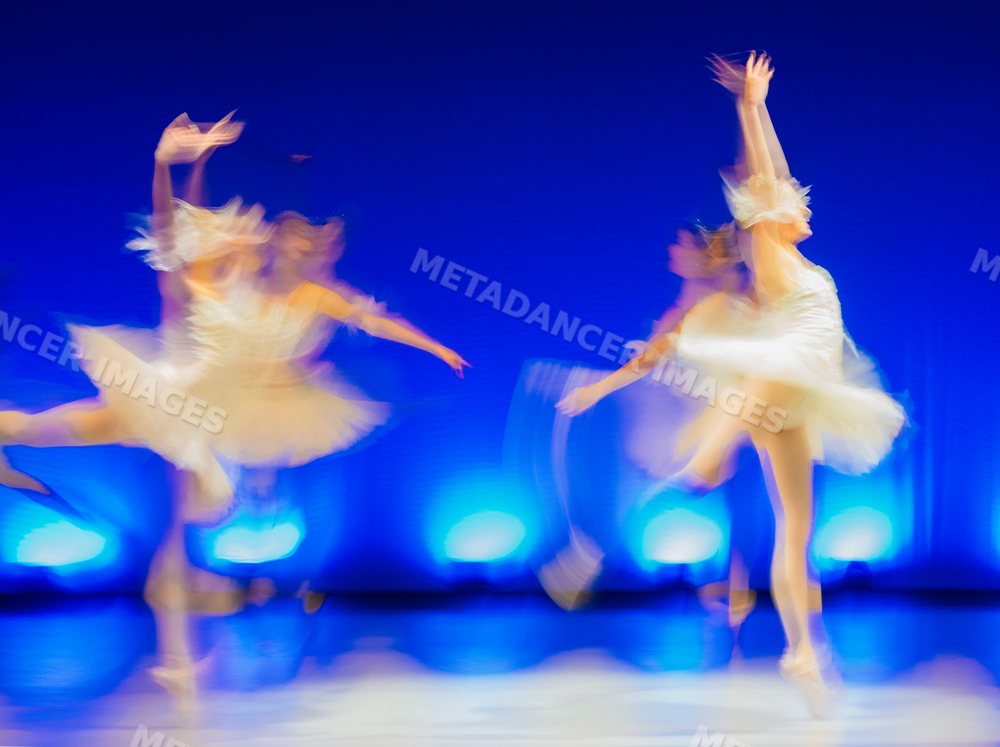 Blurred ballet dancers perform classical dance on stage with dramatic
