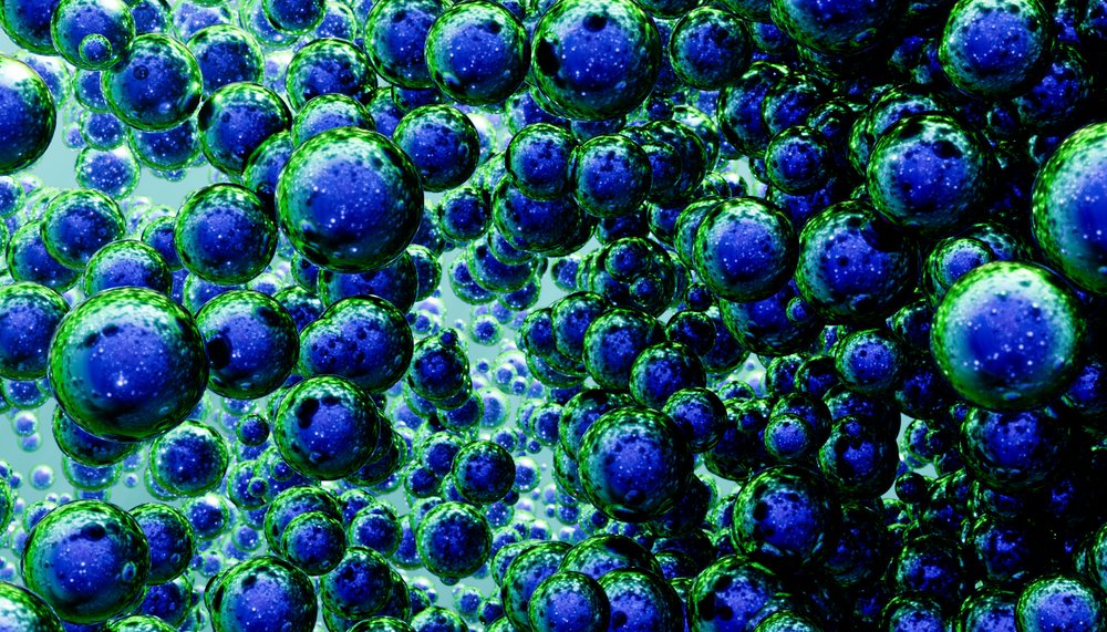 Blue bubbles with green edges floating clustered in front of a light background in a macro view.