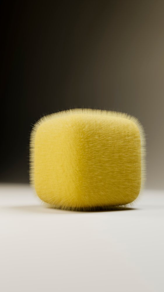 Yellow cube with a soft, furry texture and rounded edges isolated on a smooth surface under studio lighting.