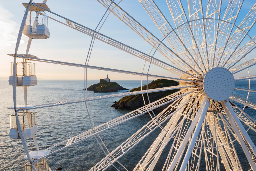 Ferris Wheel cabins and Mumbles Lighthouse on an island by the sea at sunset, Landscape, Swansea, Glamorgan, Wales.