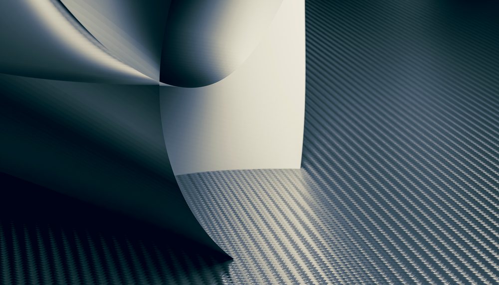 Curved stainless steel sheet on a textured metal surface showcasing industrial metalwork and material engineering.
