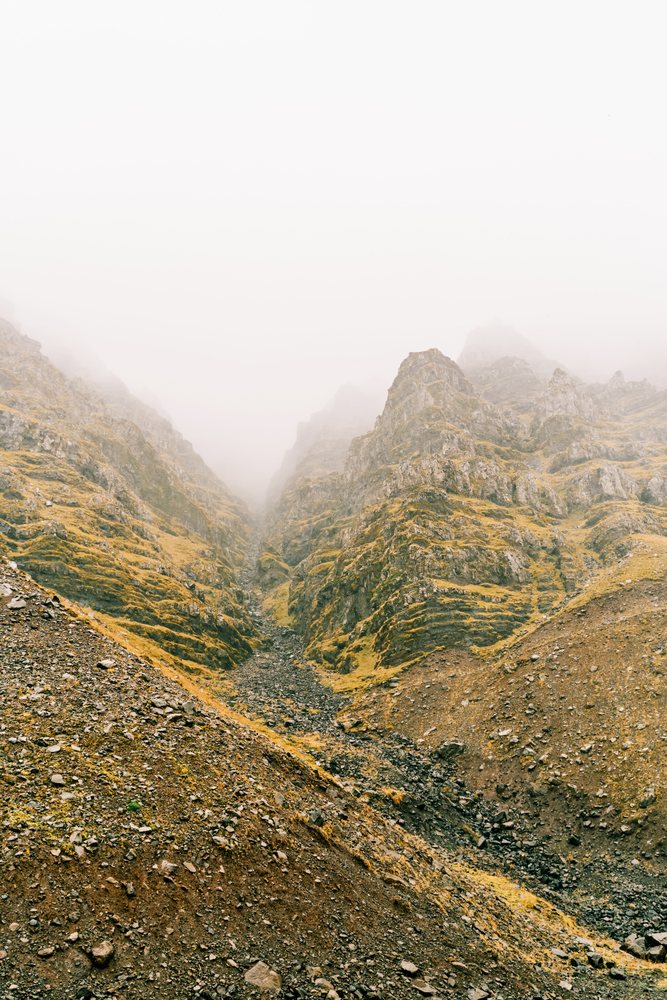 Foggy rocky mountain slopes form a remote valley landscape, Iceland.