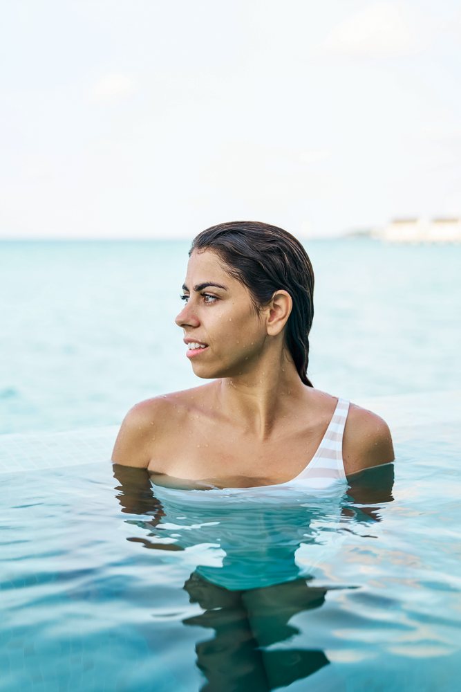 A young white woman enjoys swimming and relaxing in a pool
