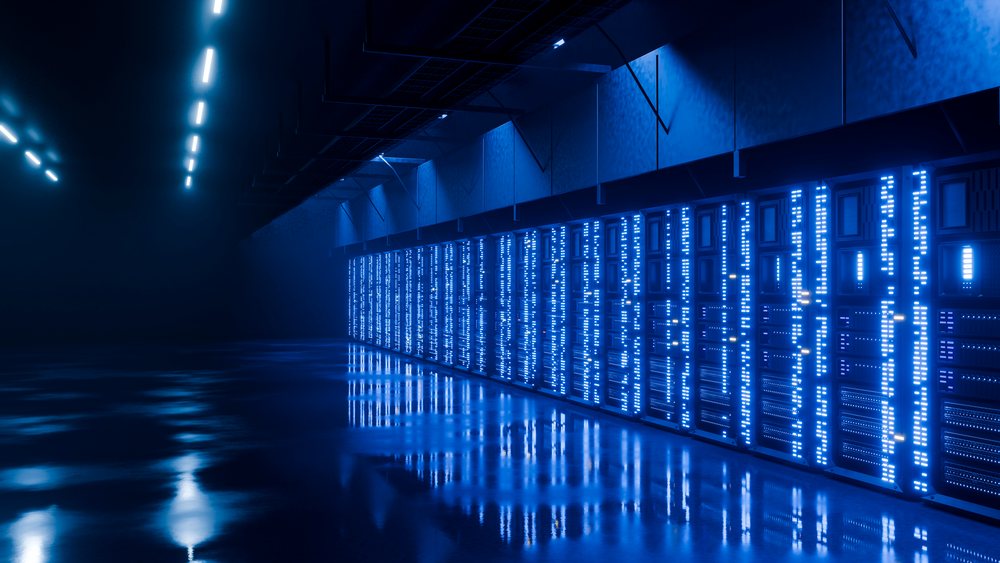 Rows of server racks with blue LED lights reflect on the polished floor inside a modern data center.