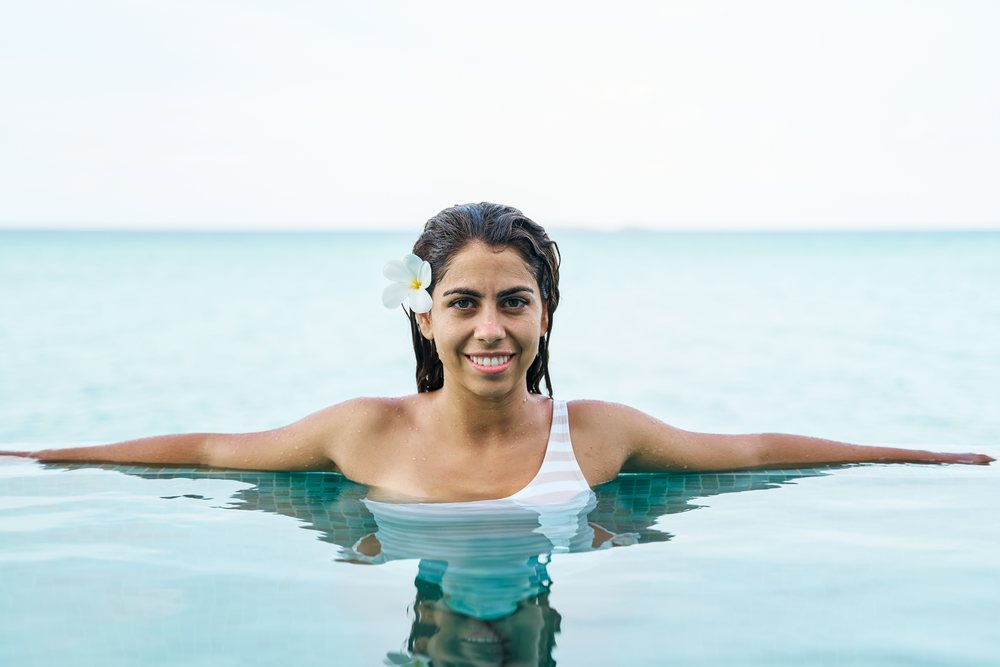 White Woman relaxing in infinity pool with flower in hair