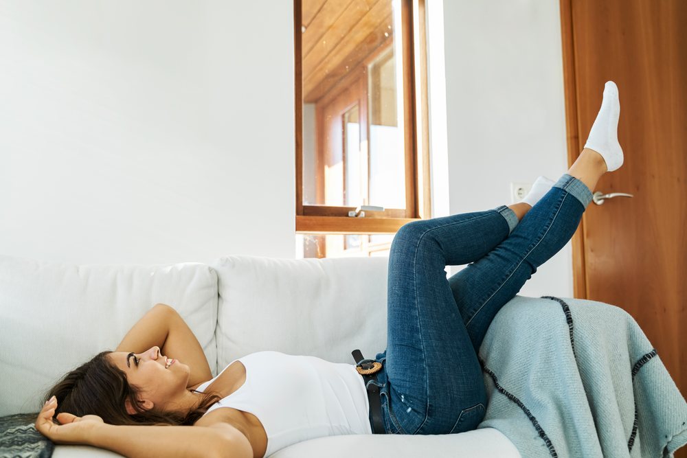 A young white woman relaxing on a couch in a cozy living room