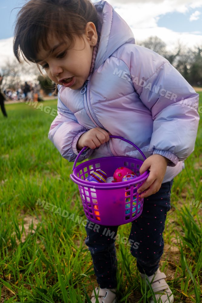 Young white girl holding a basket full of colorful eggs outdoors