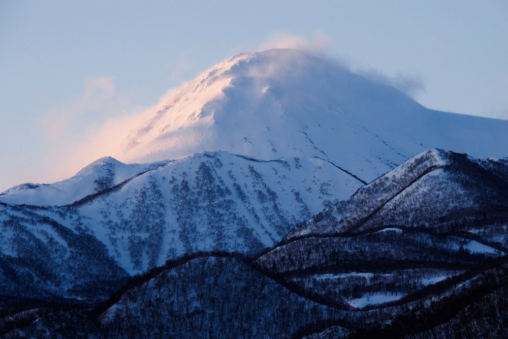 Mount Rausu snow-covered peak illuminated by the setting sun in Shiretoko National Park, Hokkaido, Japan.
