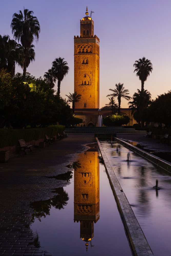 The Koutoubia Minaret with illuminated top is reflected in a water puddle at Dawn, Lifestyle, Landscape, Culture, Marrakech, Marrakesh-Safi Region, Morocco.
