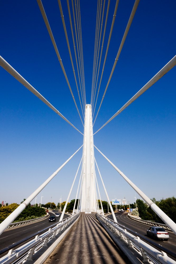 Puente de Alamillo cable-stayed bridge with tall central pylon and asphalt roadway carrying cars, Spain under clear sky, Andalucia.