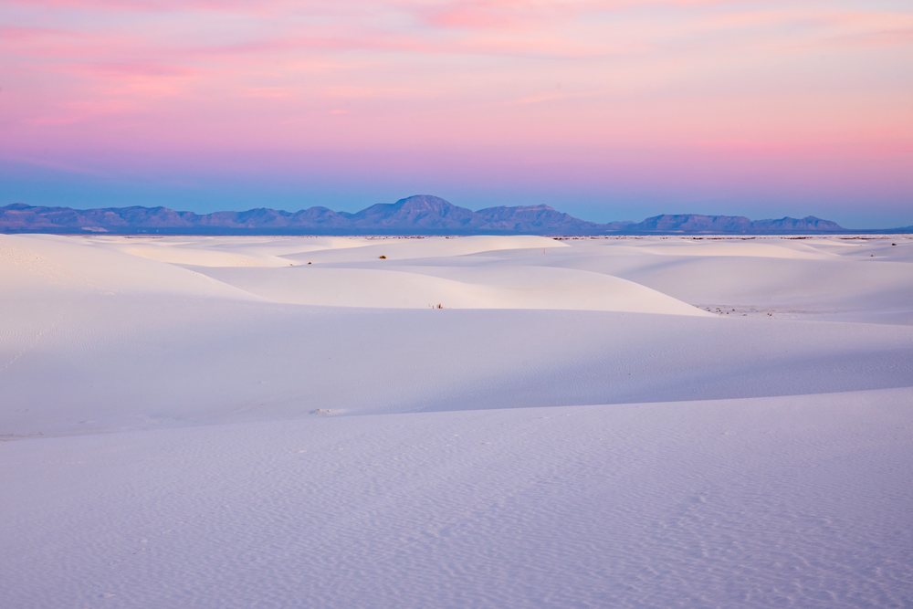 Sunrise over white sand dunes with distant mountains and a pink and blue sky at white Sands National Park, landscape, wildlife, Alamogordo, New Mexico, USA.