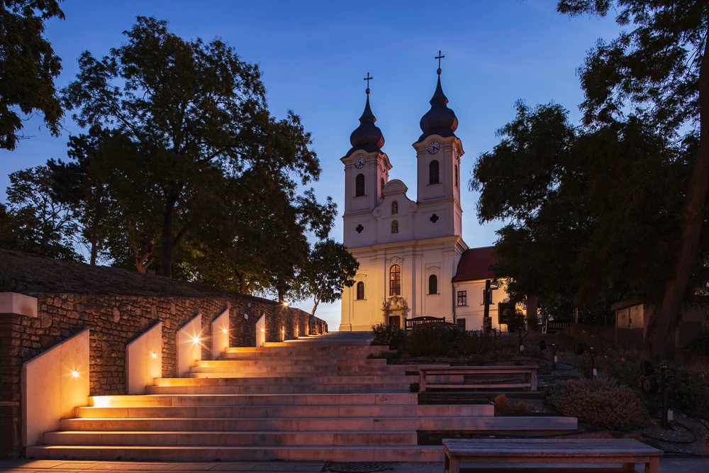 Benedictine Abbey of Tihany at Dawn with illuminated stone steps, benches, and surrounding trees, Cityscapes, Hungary.
