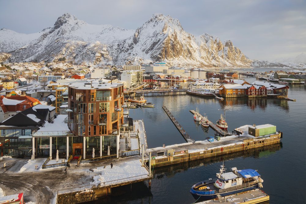 Sunrise over Svolvaer harbor with snow-covered mountains, fishing boats, and calm water, Landscape, Lofoten, Norway.