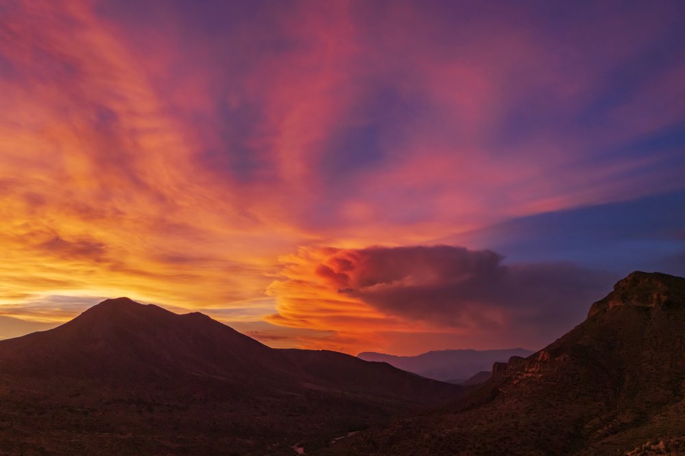 Thunderstorm clouds over a mountainous landscape at Sunset with vibrant orange and purple sky colors, Storm Chasing, Weather, Environment, Globe, Arizona, USA.