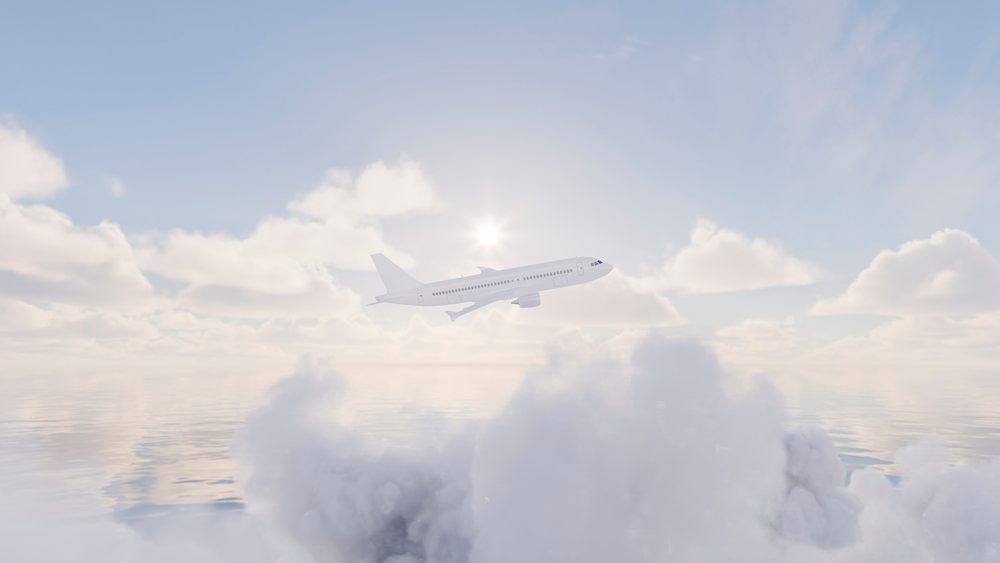 Airplane flying above clouds with sun shining and water reflection during the day.