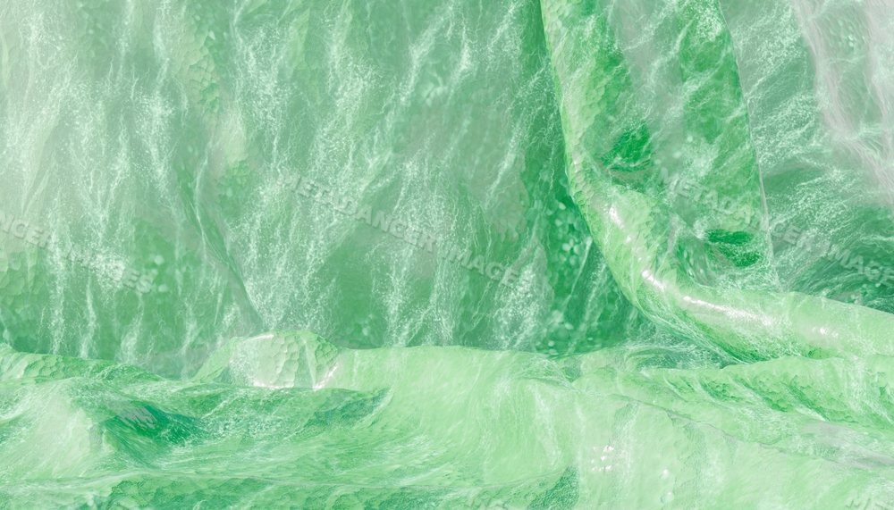 Close-up view of crumpled shiny green fabric with textured folds