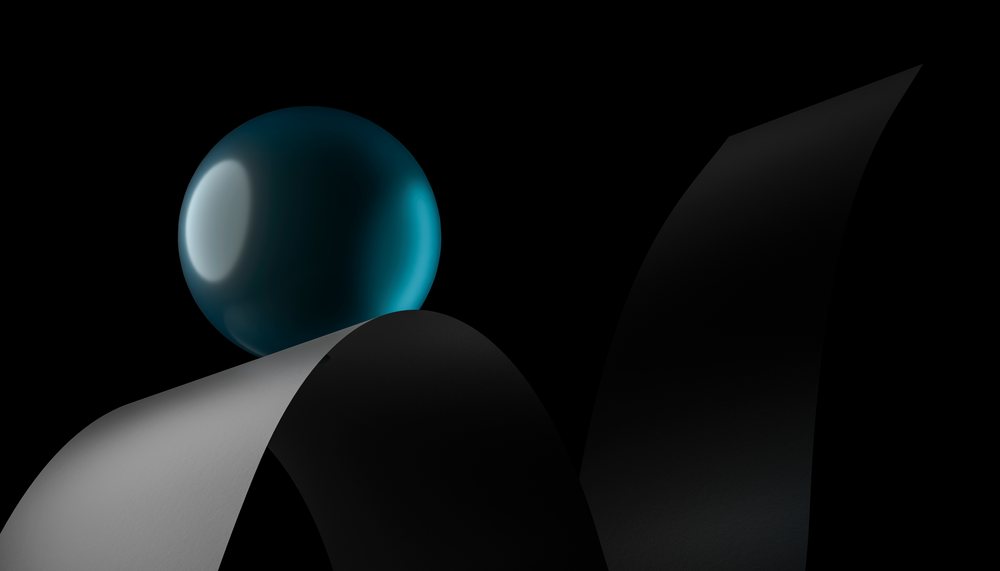 A blue glossy sphere balanced on a curved black and gray paper strip against a black background in a minimalist studio setting.