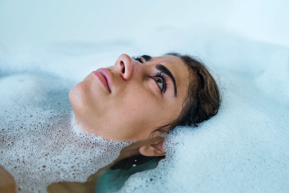 A woman rests with her head on bubbly water in a soothing bath set in the, Maldives.
