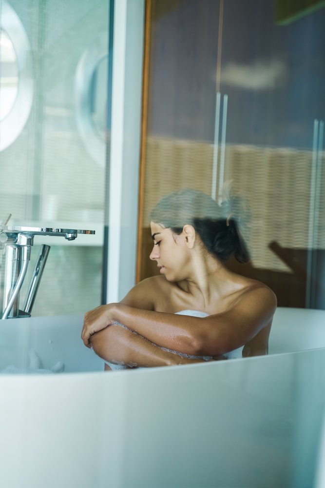 A woman relaxes in a bubble bath inside a modern bathroom in the, Maldives.