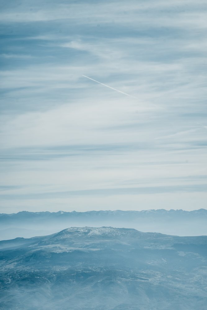 Aerial view of a misty mountain landscape with a distant mountain range beneath a cloudy sky, mountaineering, climbing, Nepal.