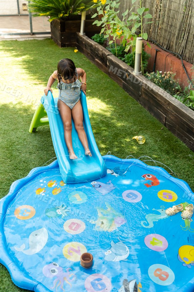 Young white girl sliding into inflatable splash pool