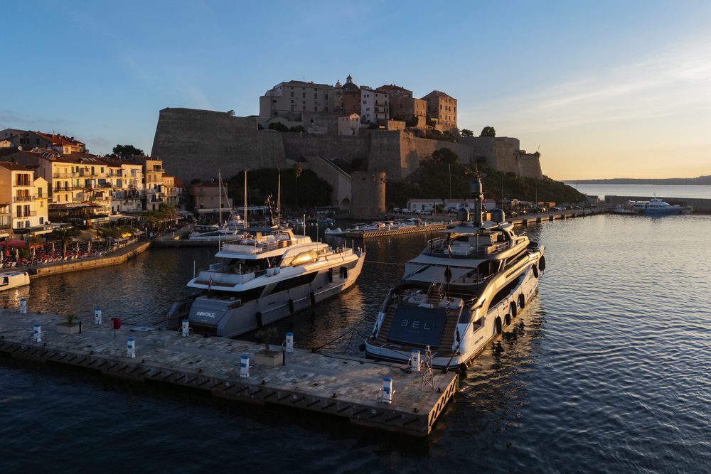 Citadel on a raised hill overlooking yachts moored at the pier and harbor water at Sunrise, Travel Photography, Calvi, Corsica, France.