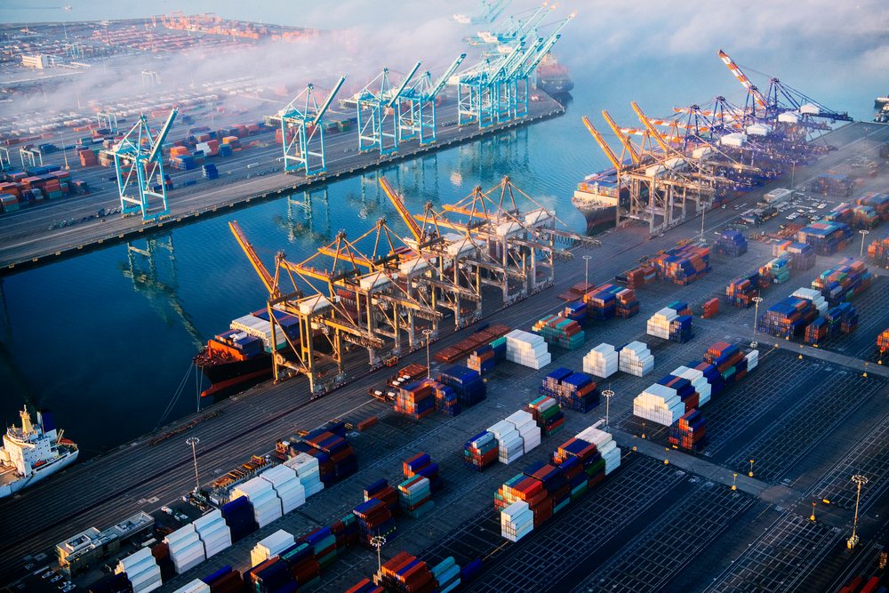 Shipping containers and container cranes at a cargo terminal with docked ships and an industrial shipping yard at a major seaport in lifornia, major California port, CA, USA.