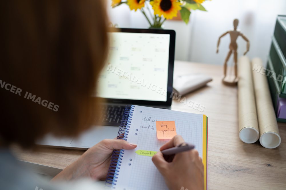 A white woman writes important notes in her notebook