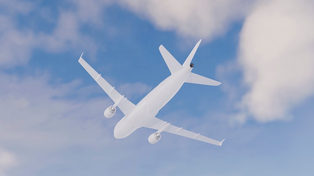 White commercial airplane flying in a blue sky with clouds.