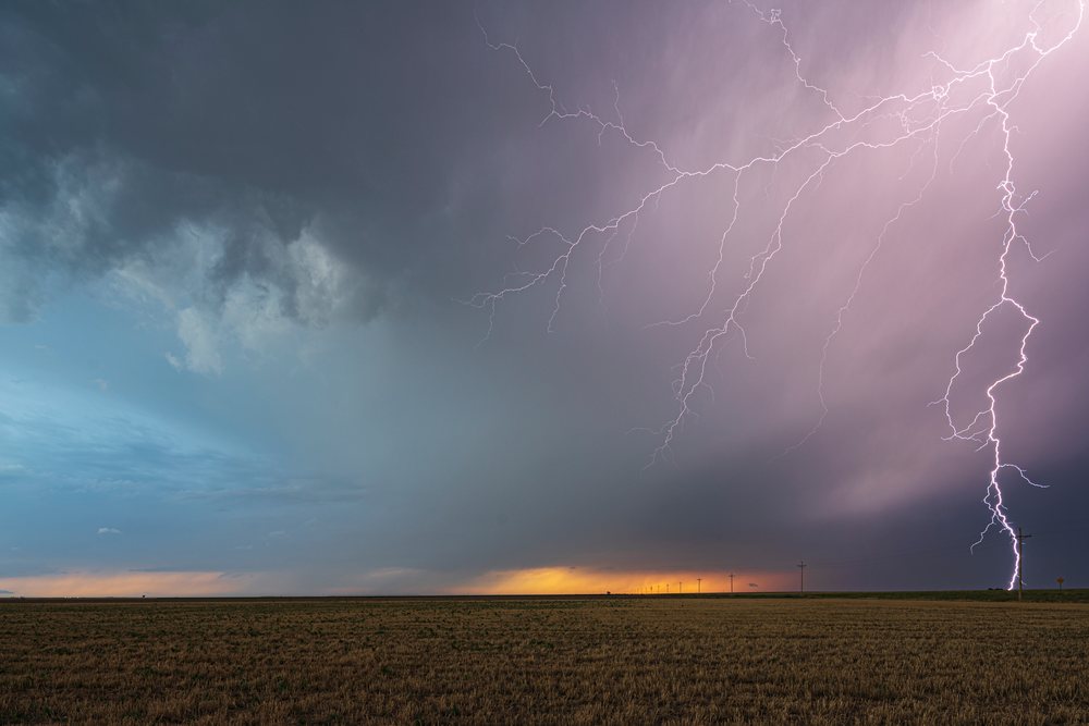 Lightning bolts strike from Storm clouds over an open agricultural field at sunset, Storm Chasing, Weather, Environment, Ulysses, Kansas, USA.