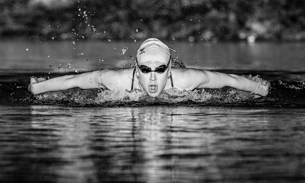 Swimmer performing butterfly stroke with intense focus and water splashing around, USA.