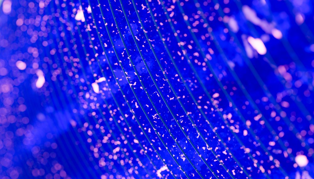 Close-up abstract pattern of curved lines and glowing blue and pink dots creating a vibrant and dynamic visual texture.