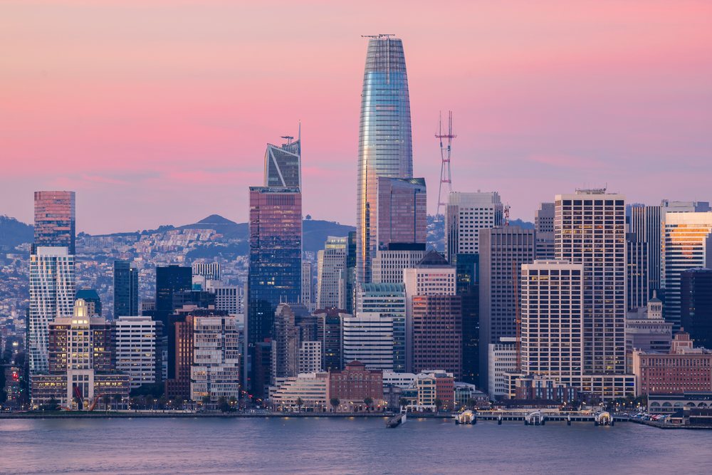 San Francisco Downtown skyline featuring Salesforce Tower and waterfront at sunset with pink sky and hills in background, City, Cityscapes, City Life, California, USA.