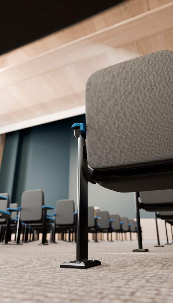 Rows of grey conference chairs with blue armrests arranged in a modern indoor meeting room with blue walls and patterned carpet.