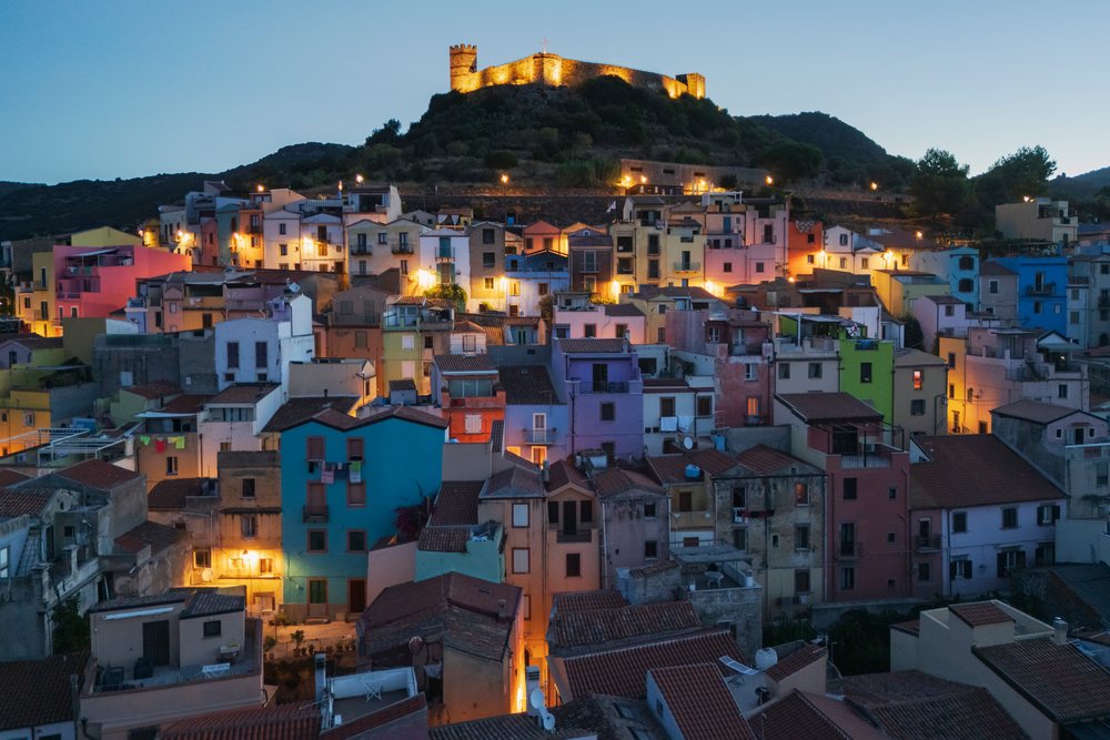 Old Town of Bosa at dawn with an illuminated hilltop castle and colorful Mediterranean residential buildings, Travel Images, Sardinia, Italy.