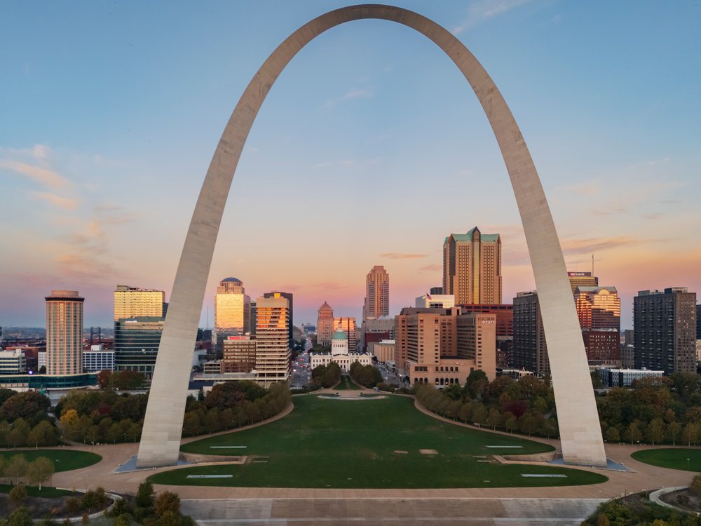 The Gateway Arch at sunrise with St Louis city skyline and urban park, Americana, Historic, Missouri, USA.