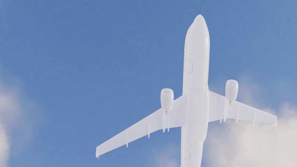White commercial airplane flying in clear blue sky with some clouds.