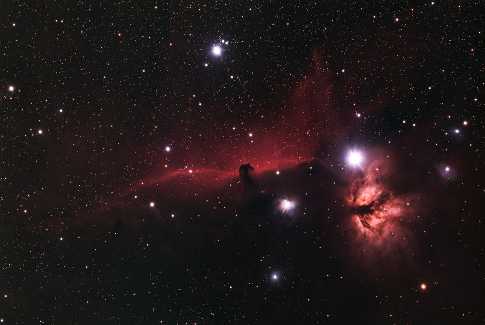 Nebula glowing red against a dark star-filled background in deep space astrophotography.